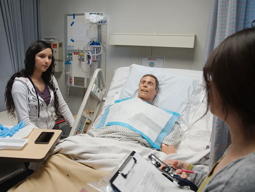 Medical student learning with a mannequin in a hospital bed