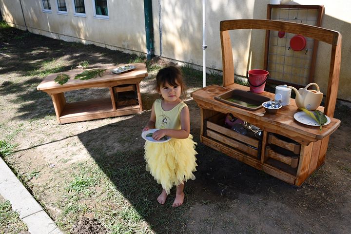 A child plays among outdoor furniture