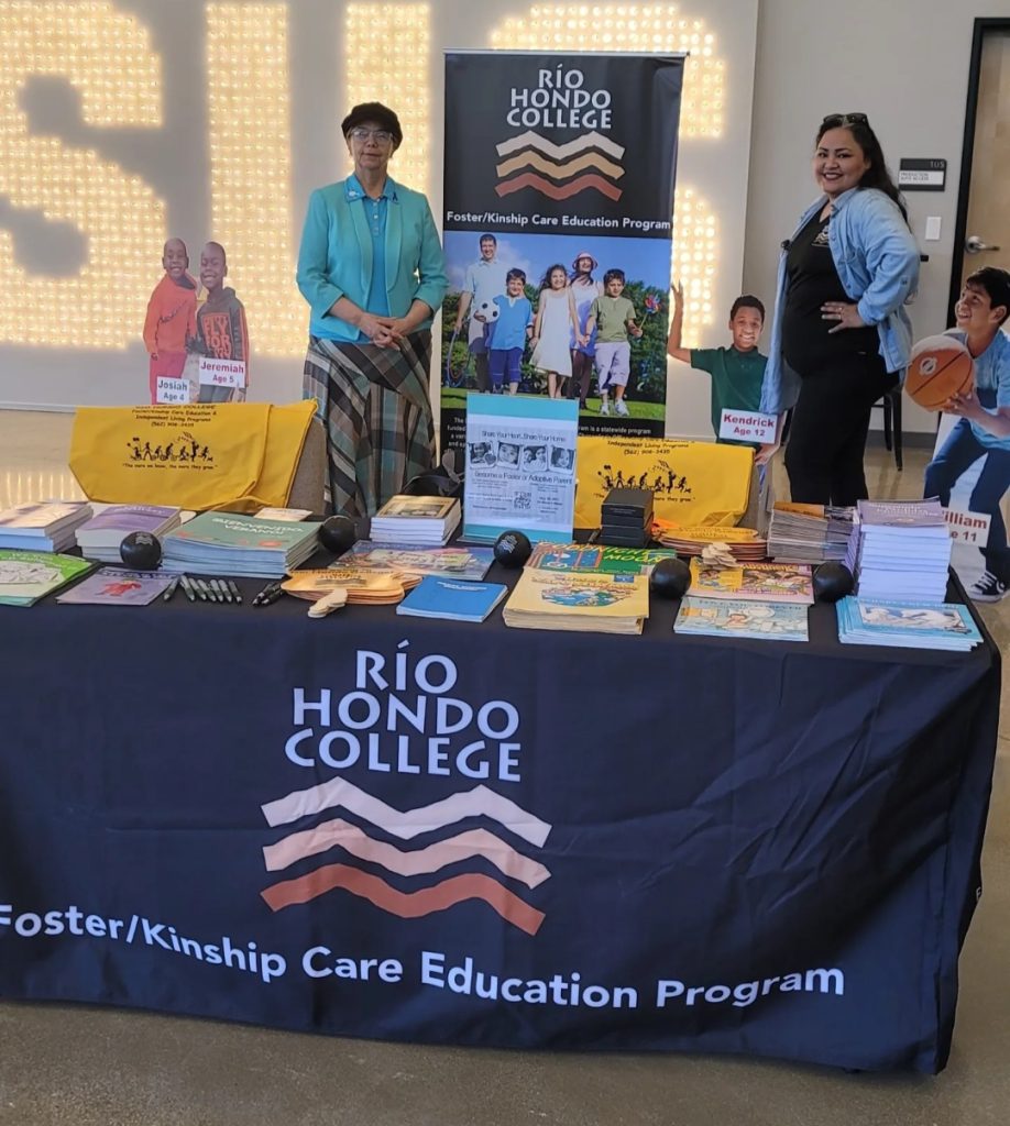 Two women with display booth, handing out information for Foster/Kinship Care Education Program